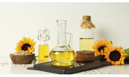 Olejový lis BOLEX Group pri práci: do násypky sa sypú semienka slnečnice a z výstupu tečie čerstvý p